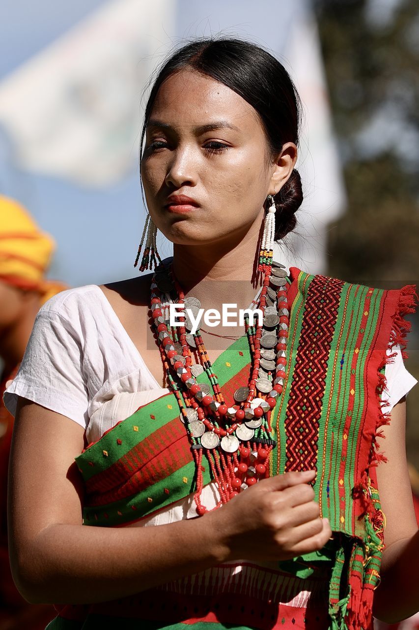 adult, women, one person, young adult, traditional clothing, clothing, portrait, arts culture and entertainment, waist up, lifestyles, female, tradition, looking, person, nature, outdoors, spring, emotion, jewelry, front view, tribe, fashion, standing, indigenous culture, focus on foreground, music, red, serious
