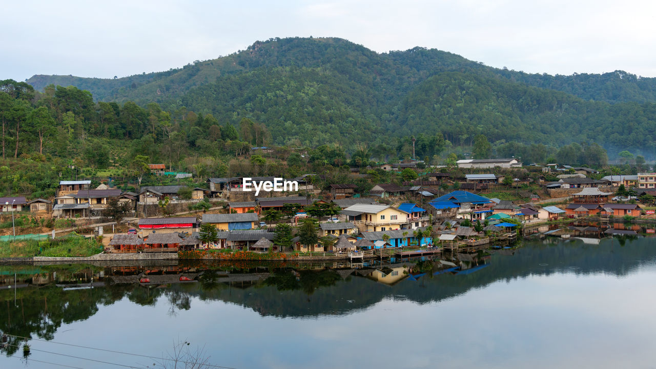 BUILDINGS BY LAKE AGAINST SKY