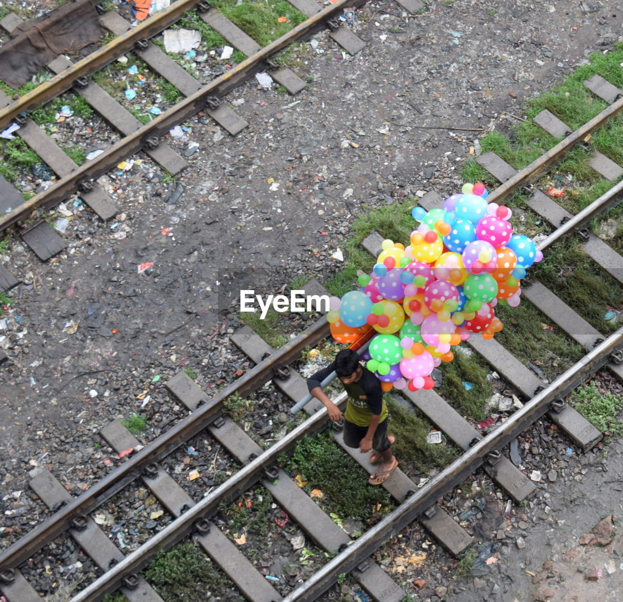 High angle view of man with balloons on railroad track