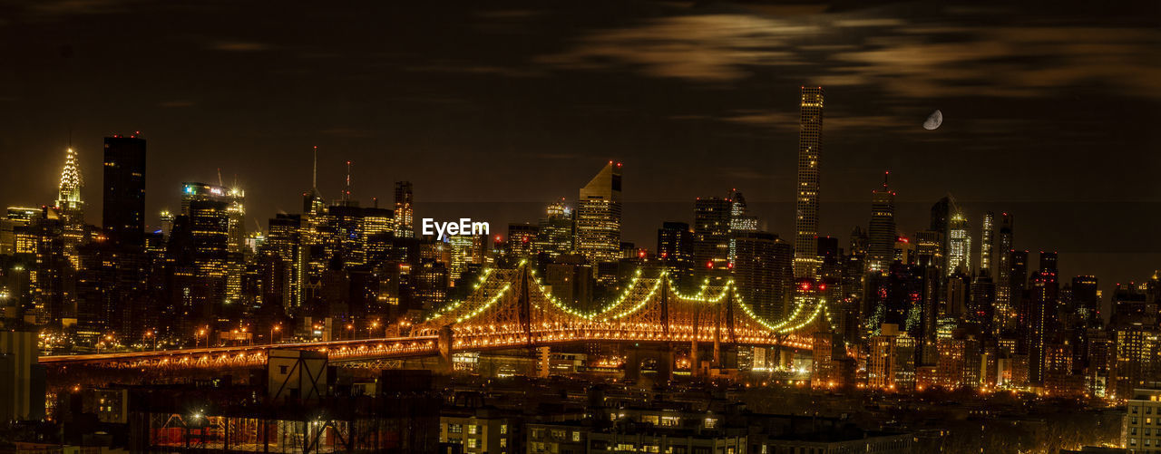 ILLUMINATED CITY BY RIVER AGAINST SKY