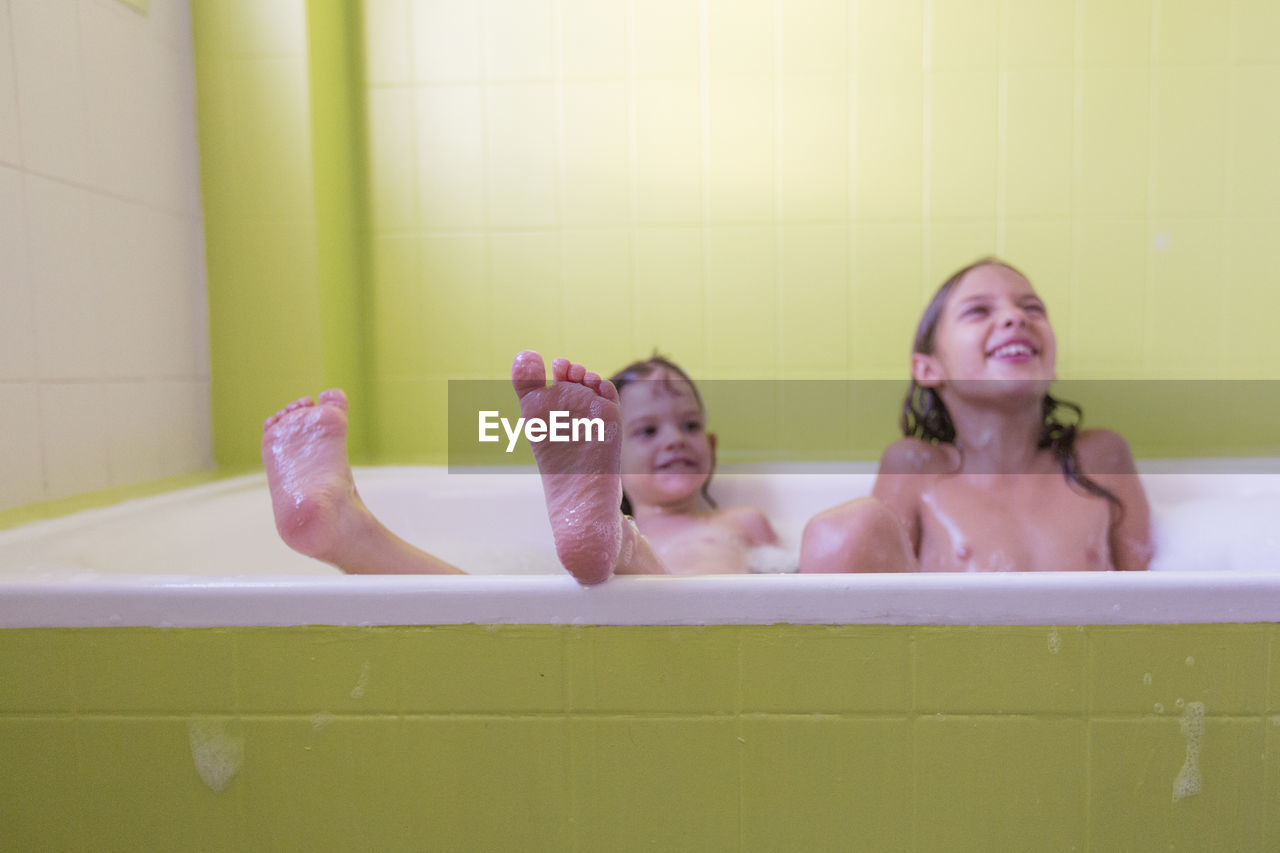 Smiling siblings playing in bathtub