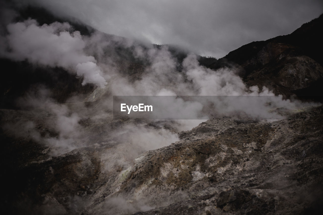 SMOKE EMITTING FROM VOLCANIC MOUNTAINS AGAINST SKY