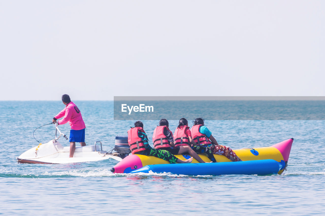 Man on jet boat by women rafting in sea