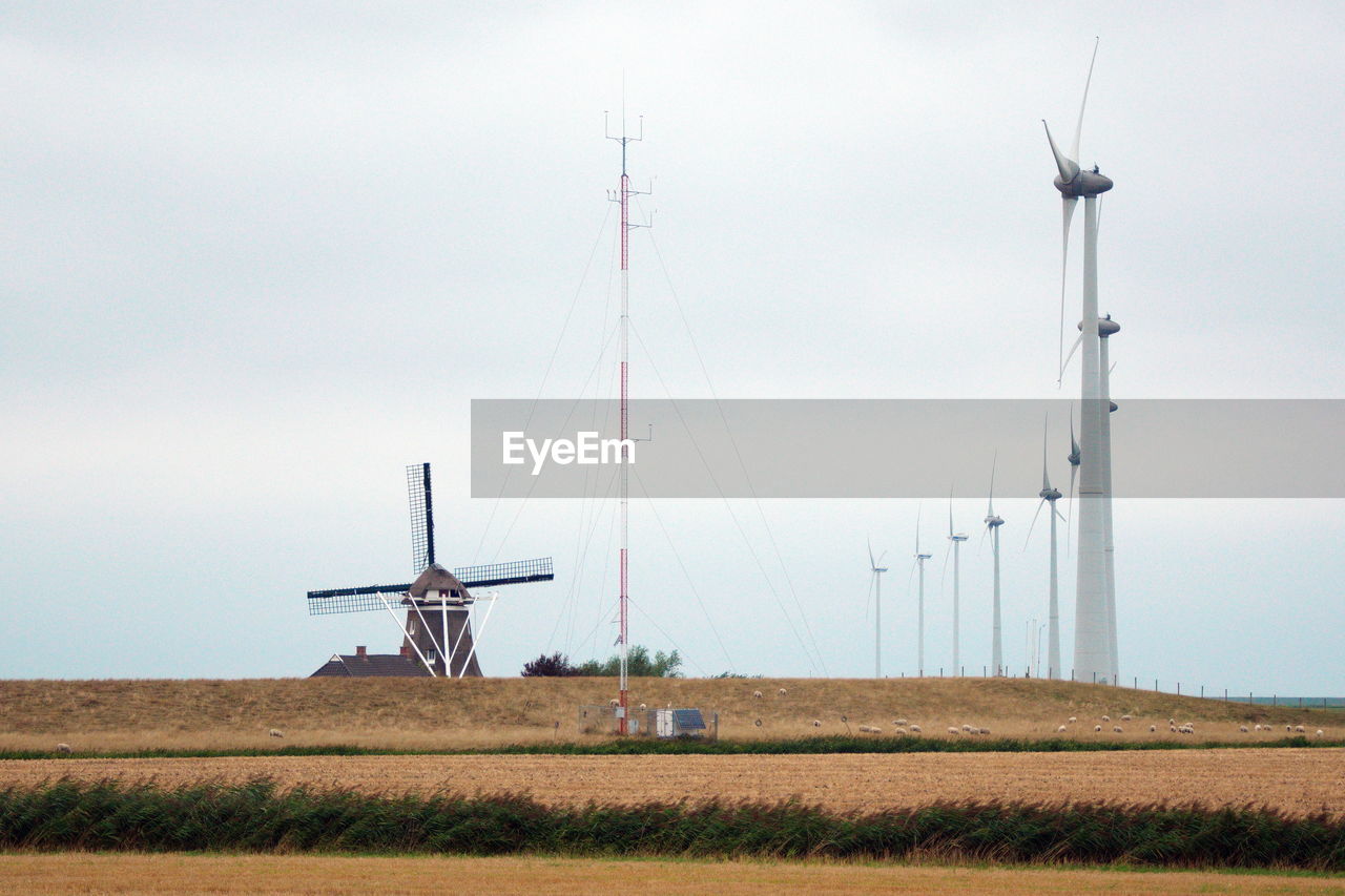 Windmills on field against sky