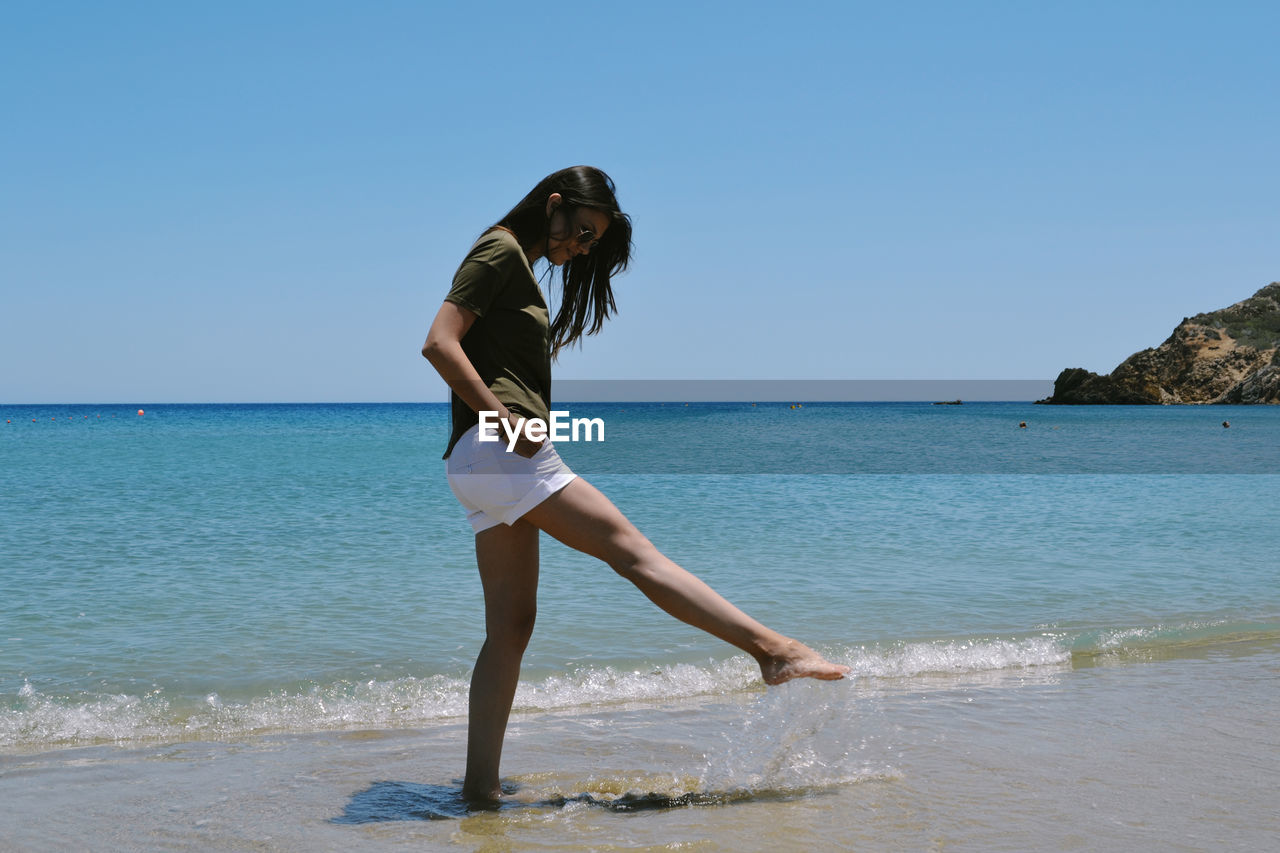 FULL LENGTH OF YOUNG WOMAN ON BEACH