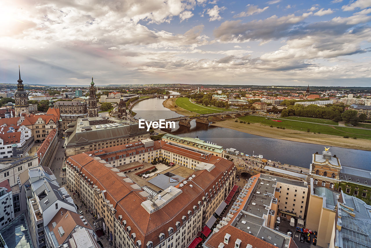 High angle view of buildings by river in city against sky