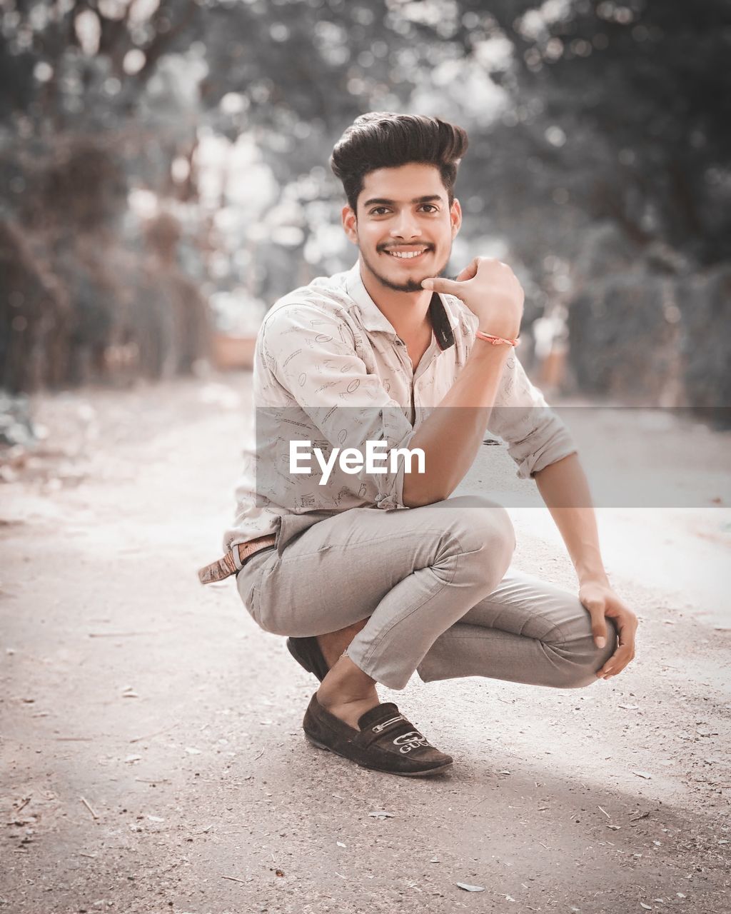 Portrait of young man crouching on road