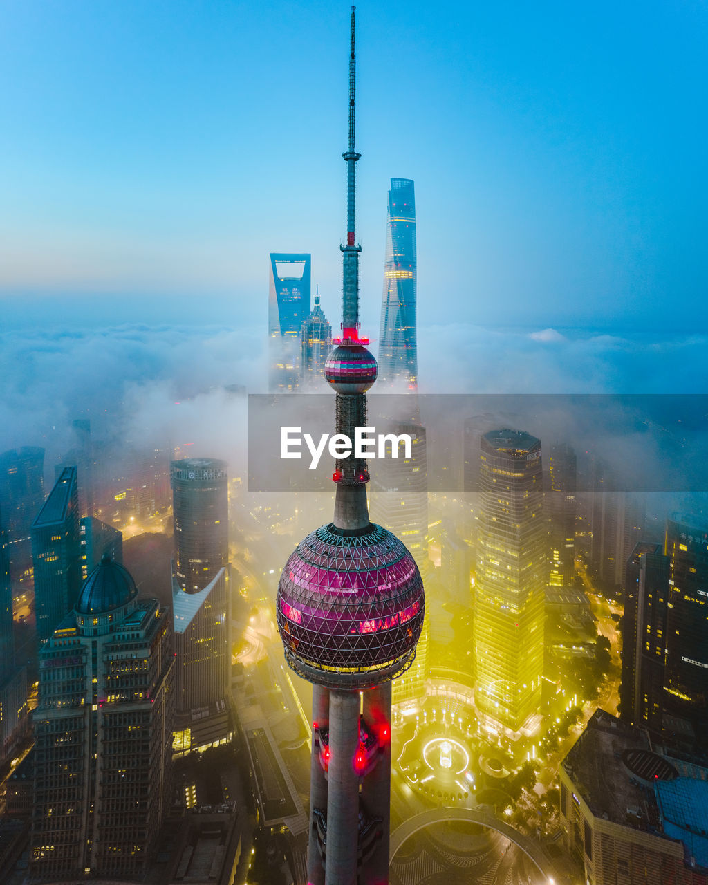 Communications tower in illuminated city against clear sky