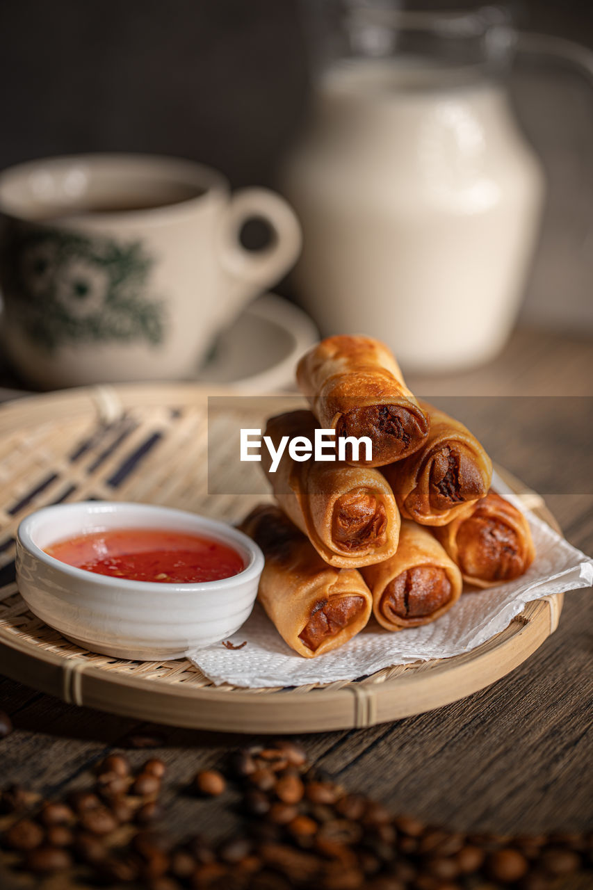 Fried spring rolls with a sweet chili sauce on a rattan plate . malaysian snacks. 