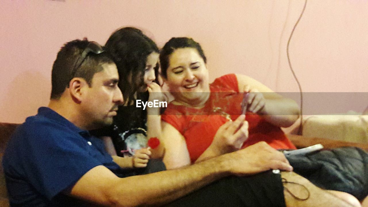 PORTRAIT OF HAPPY YOUNG COUPLE SITTING ON SOFA
