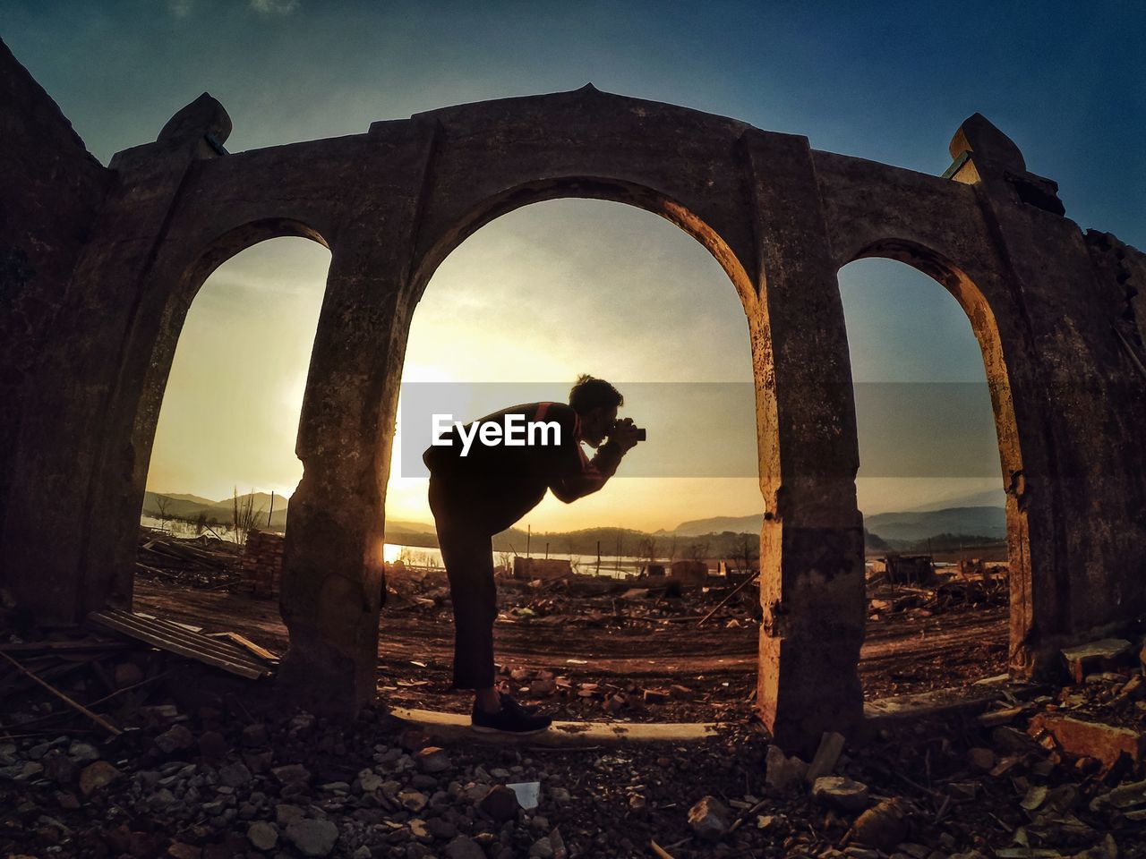 Man photographing at old ruins during sunset