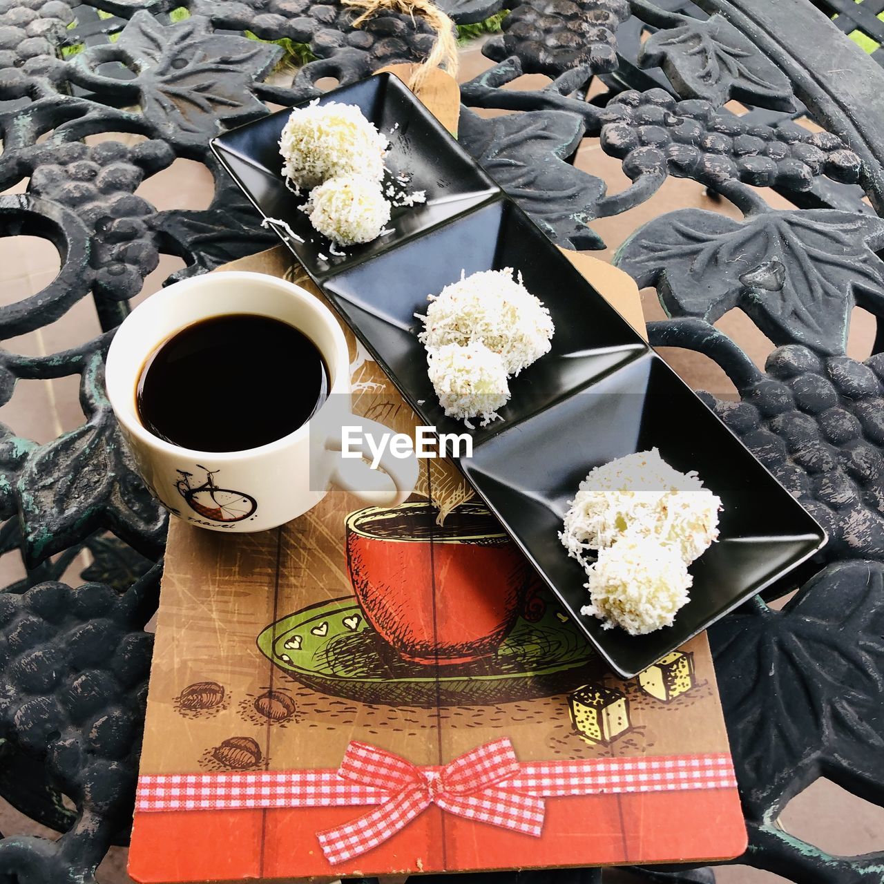 HIGH ANGLE VIEW OF BLACK COFFEE AND WHITE AND ROSES IN CUP ON TABLE