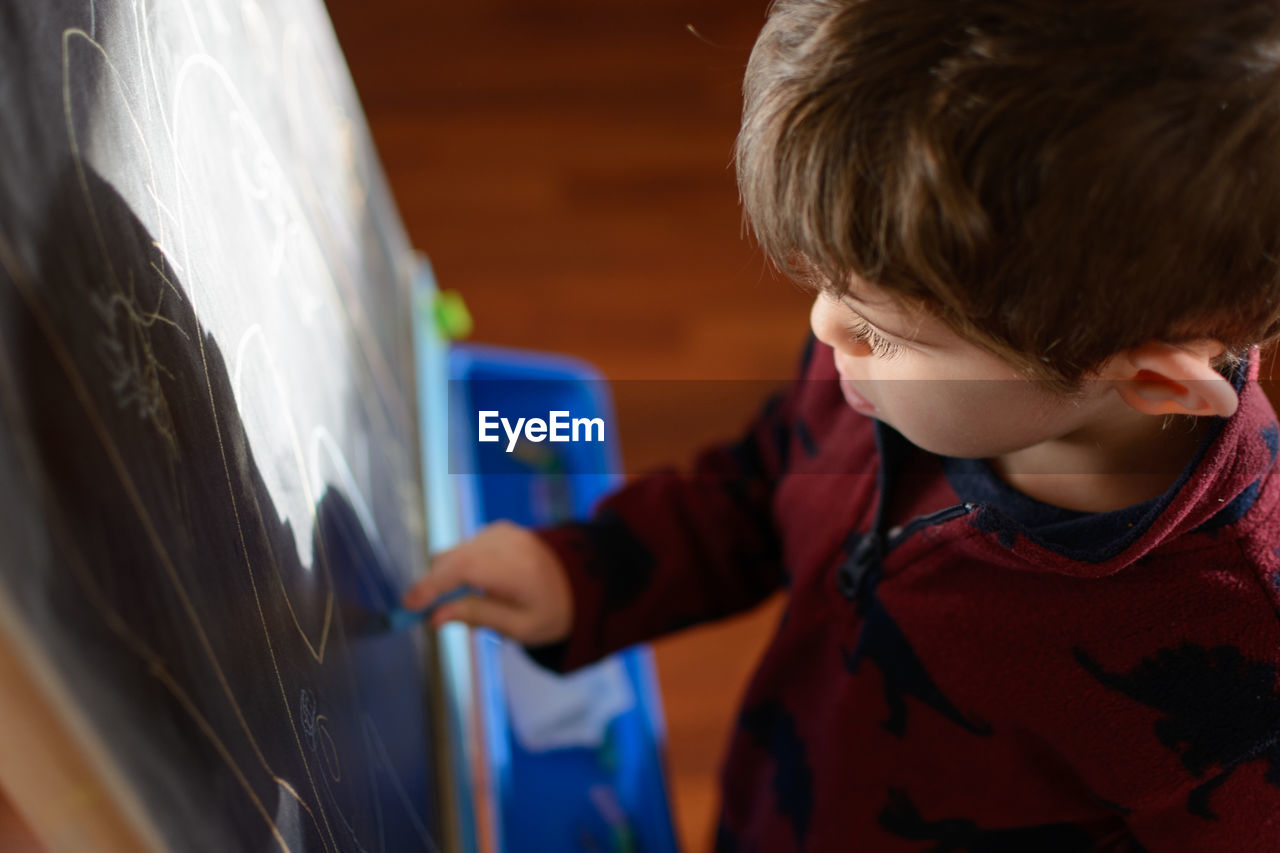 Close-up of boy drawing on blackboard