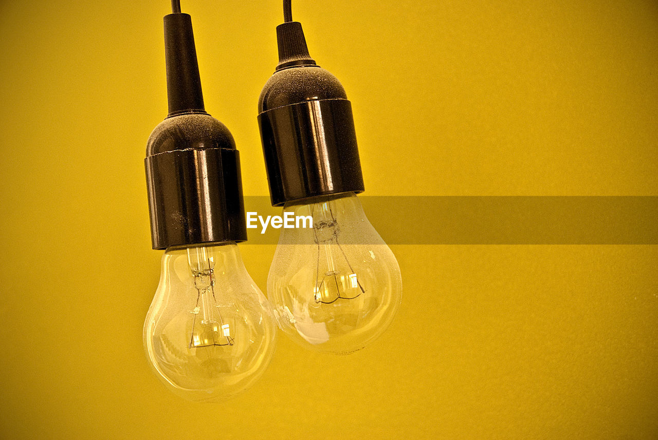 Close-up of illuminated light bulbs against yellow wall