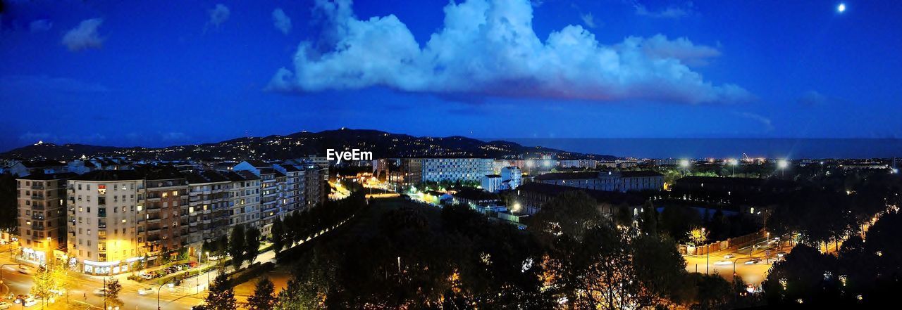 HIGH ANGLE VIEW OF ILLUMINATED BUILDINGS AGAINST SKY AT NIGHT