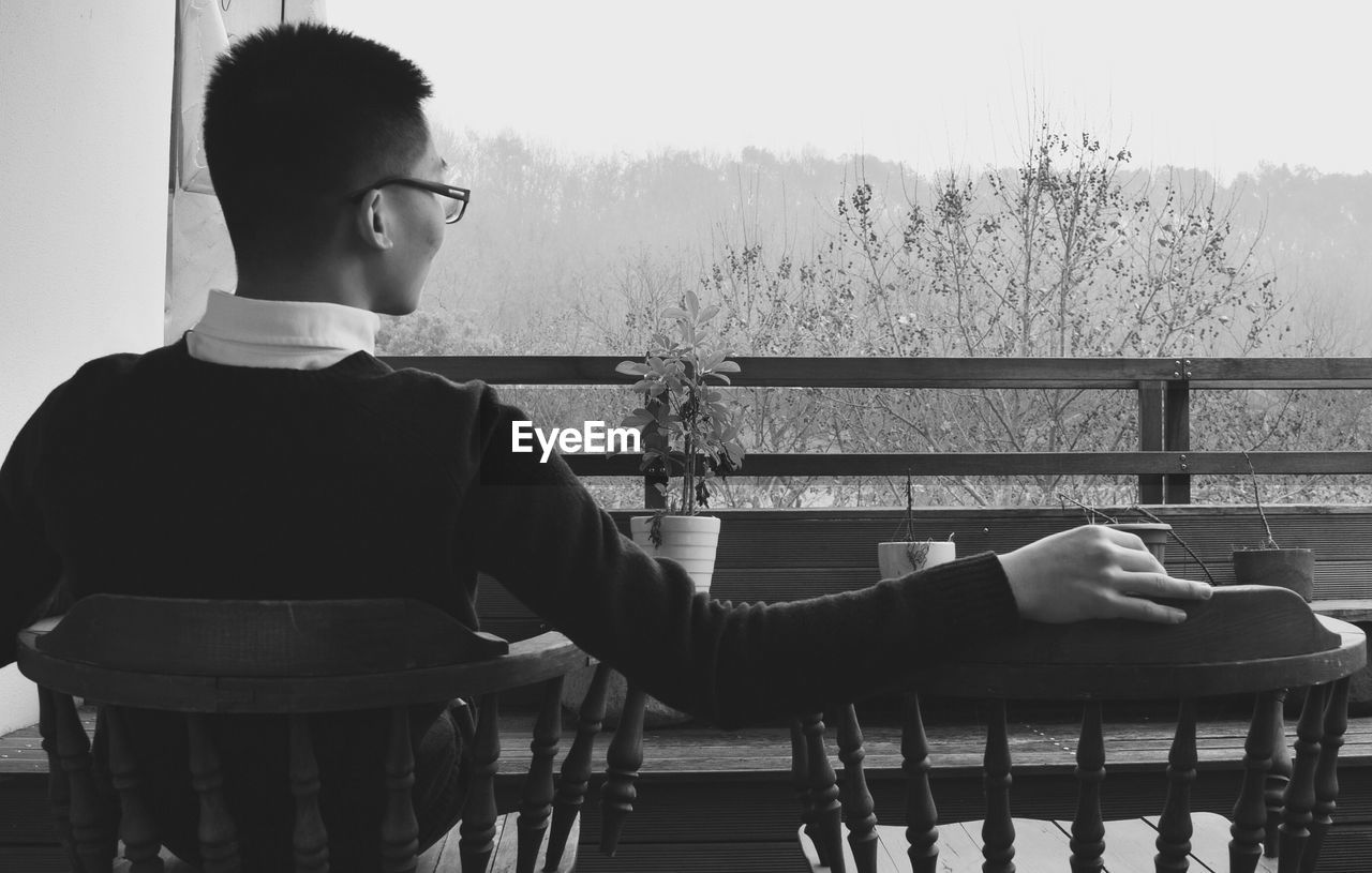 Rear view of young man sitting on chair at restaurant