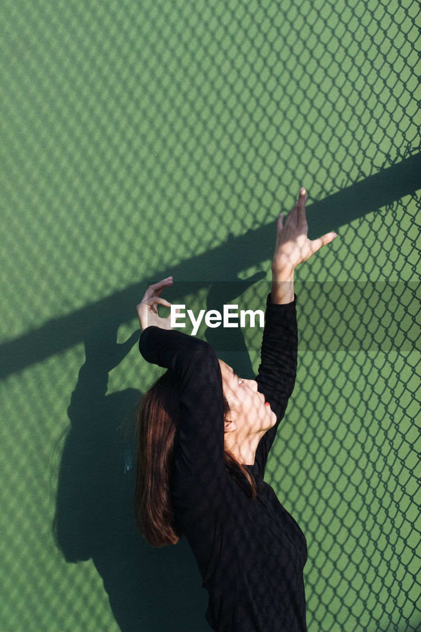 Young woman gesturing by shadow on wall