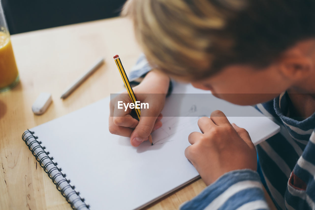 Boy making sketch on book while sitting at home