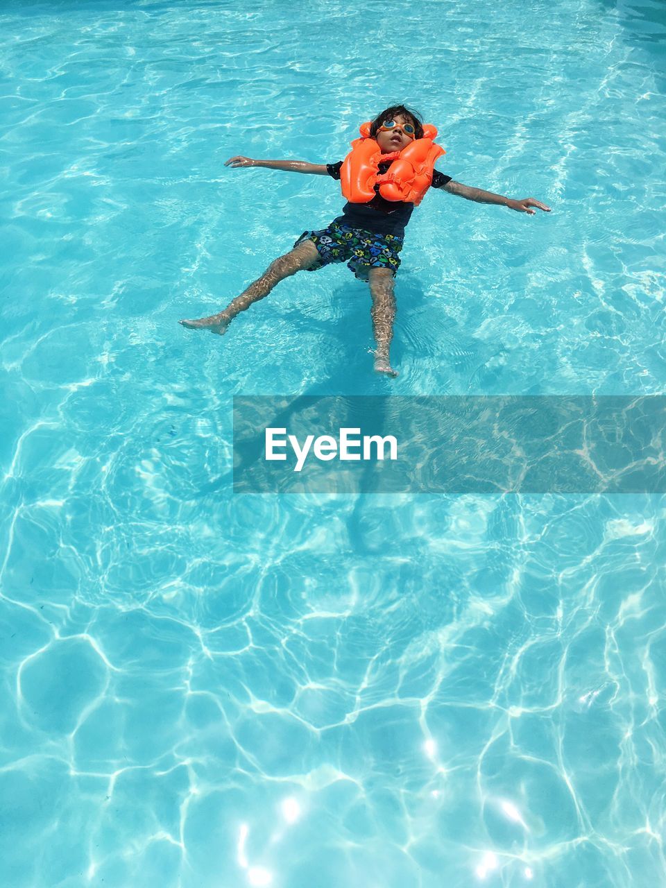 High angle view of young boy floating on water with swimming aid