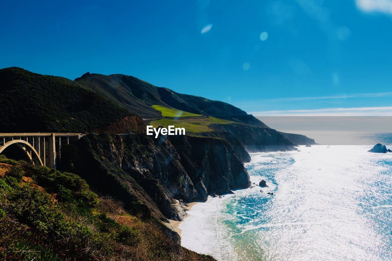 Scenic view of sea and mountains against blue sky