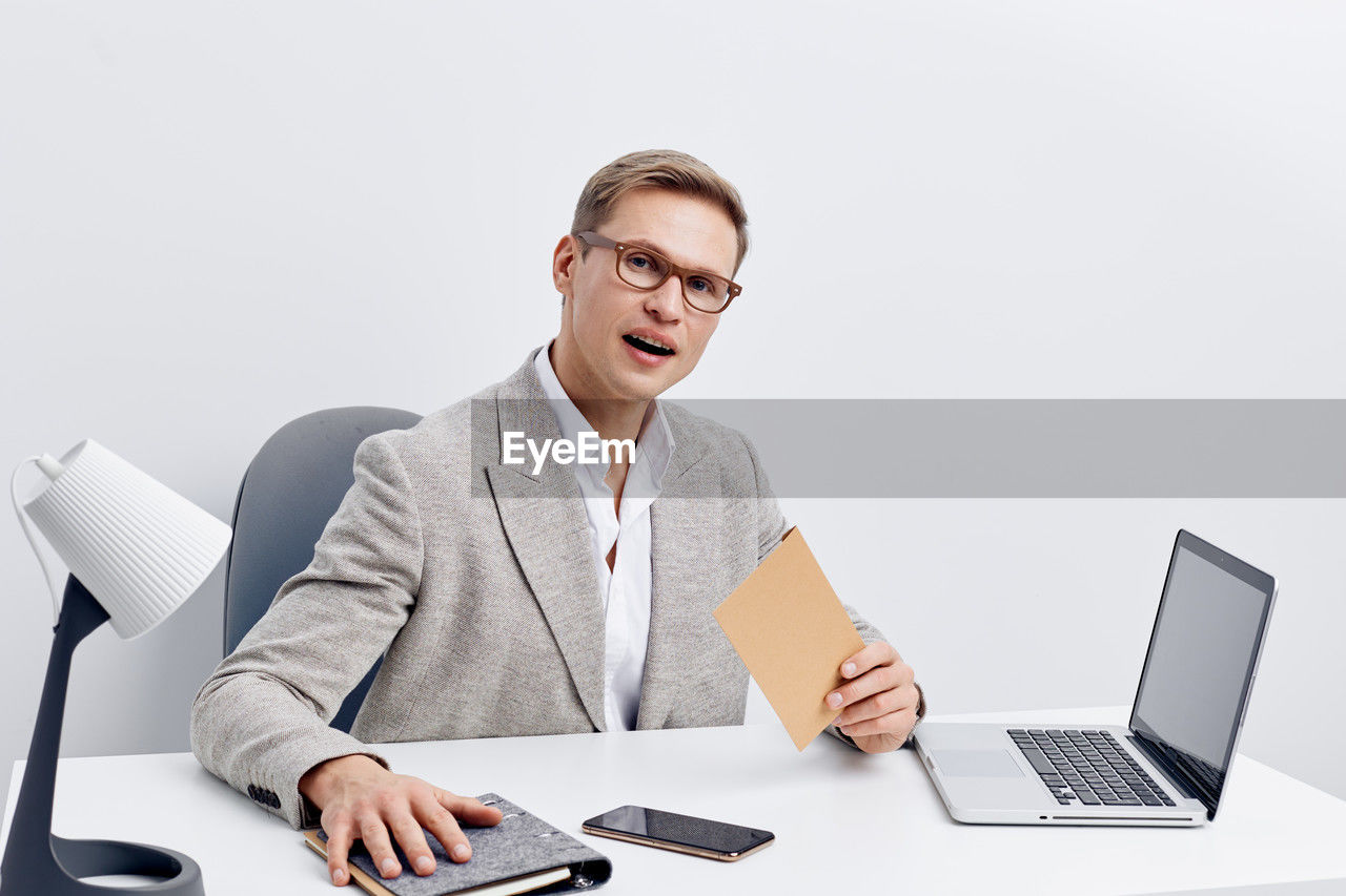 portrait of businesswoman using laptop while standing against white background