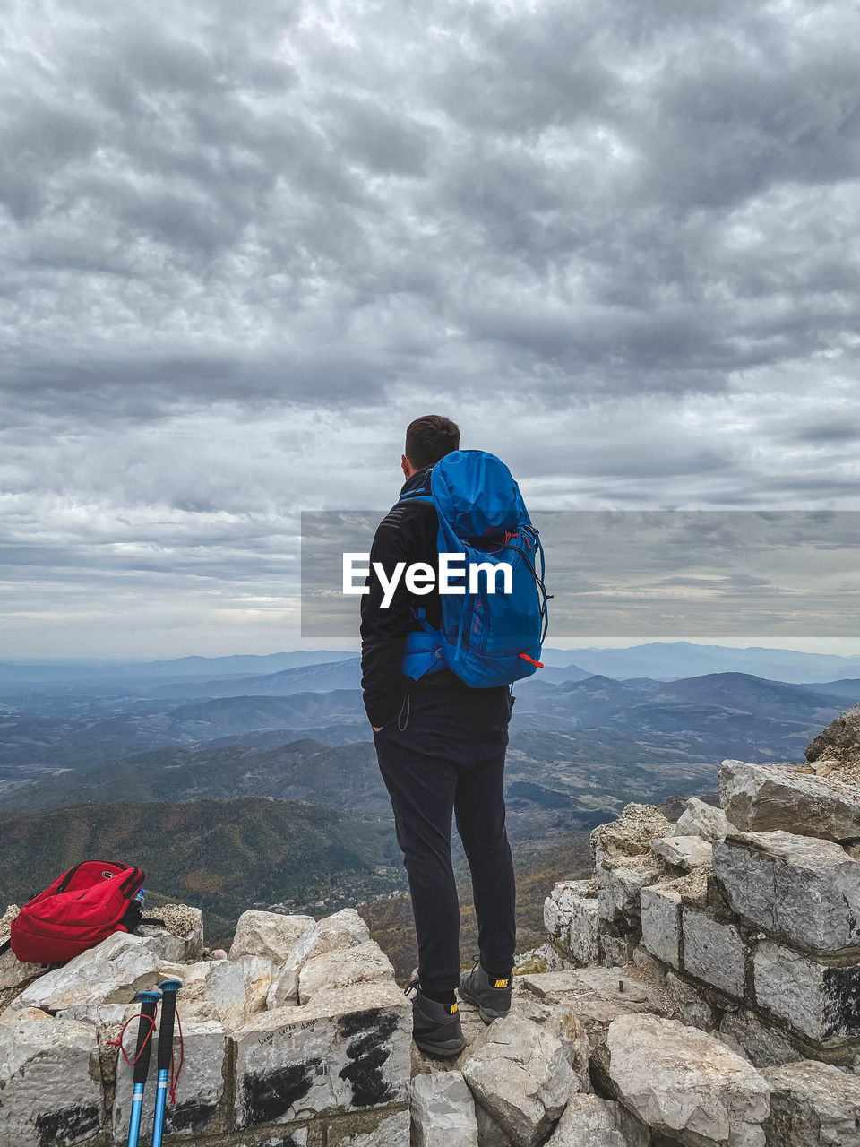 Rear view of man standing on rock against sky