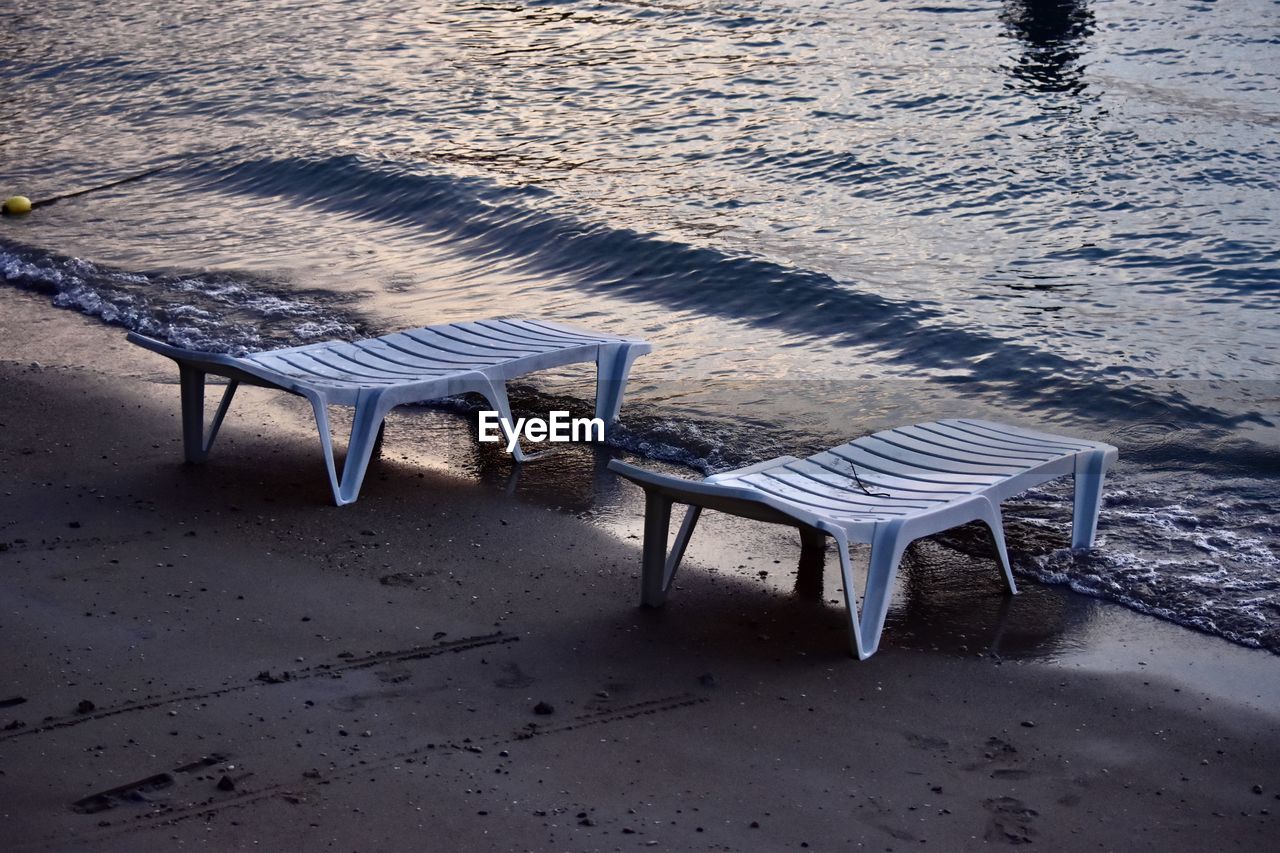 High angle view of empty chairs and table at beach