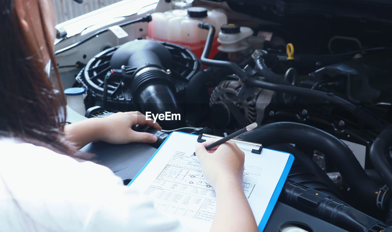 High angle view of mechanic writing in paper at auto repair shop