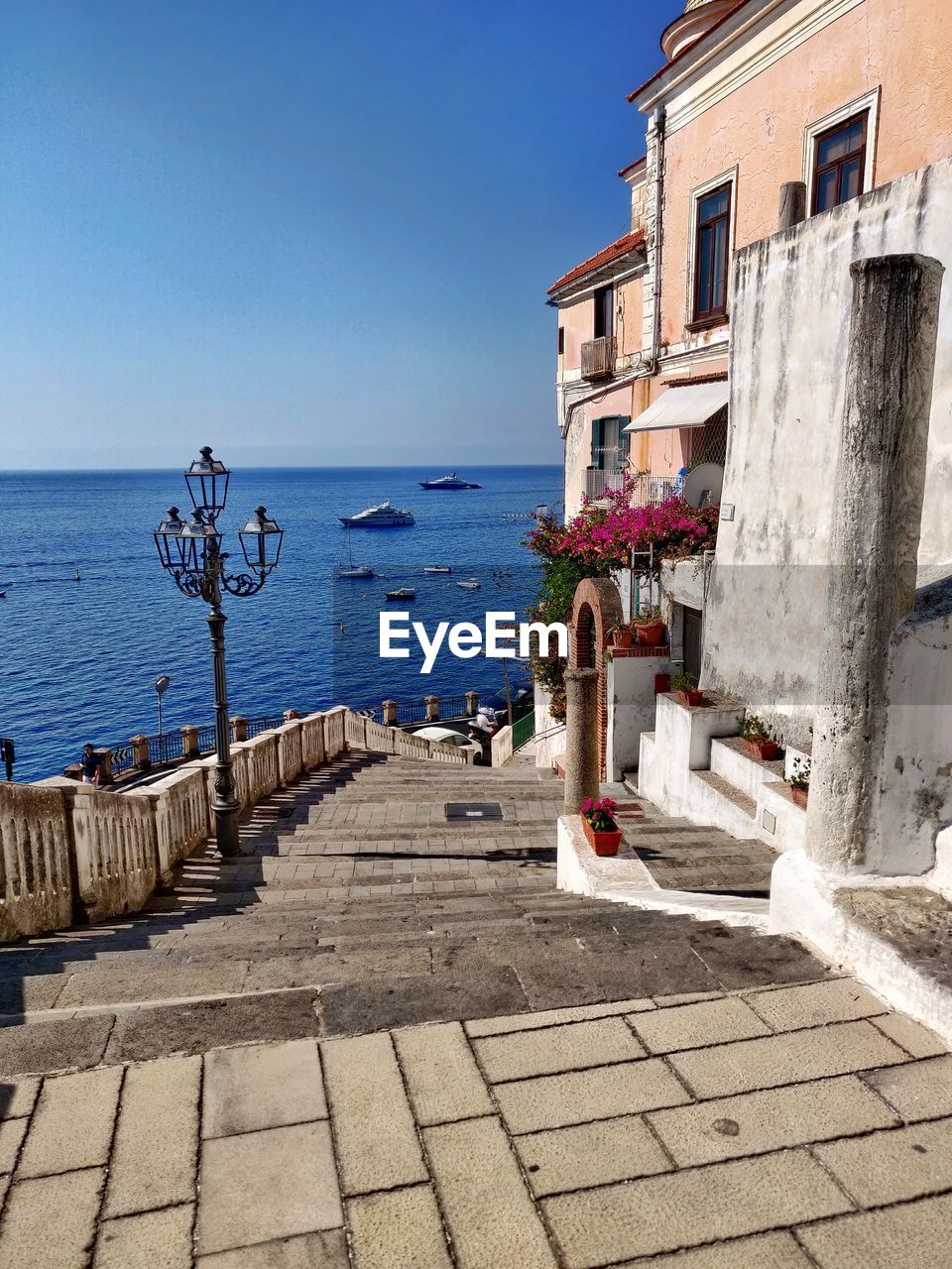 View of building by sea against clear blue sky