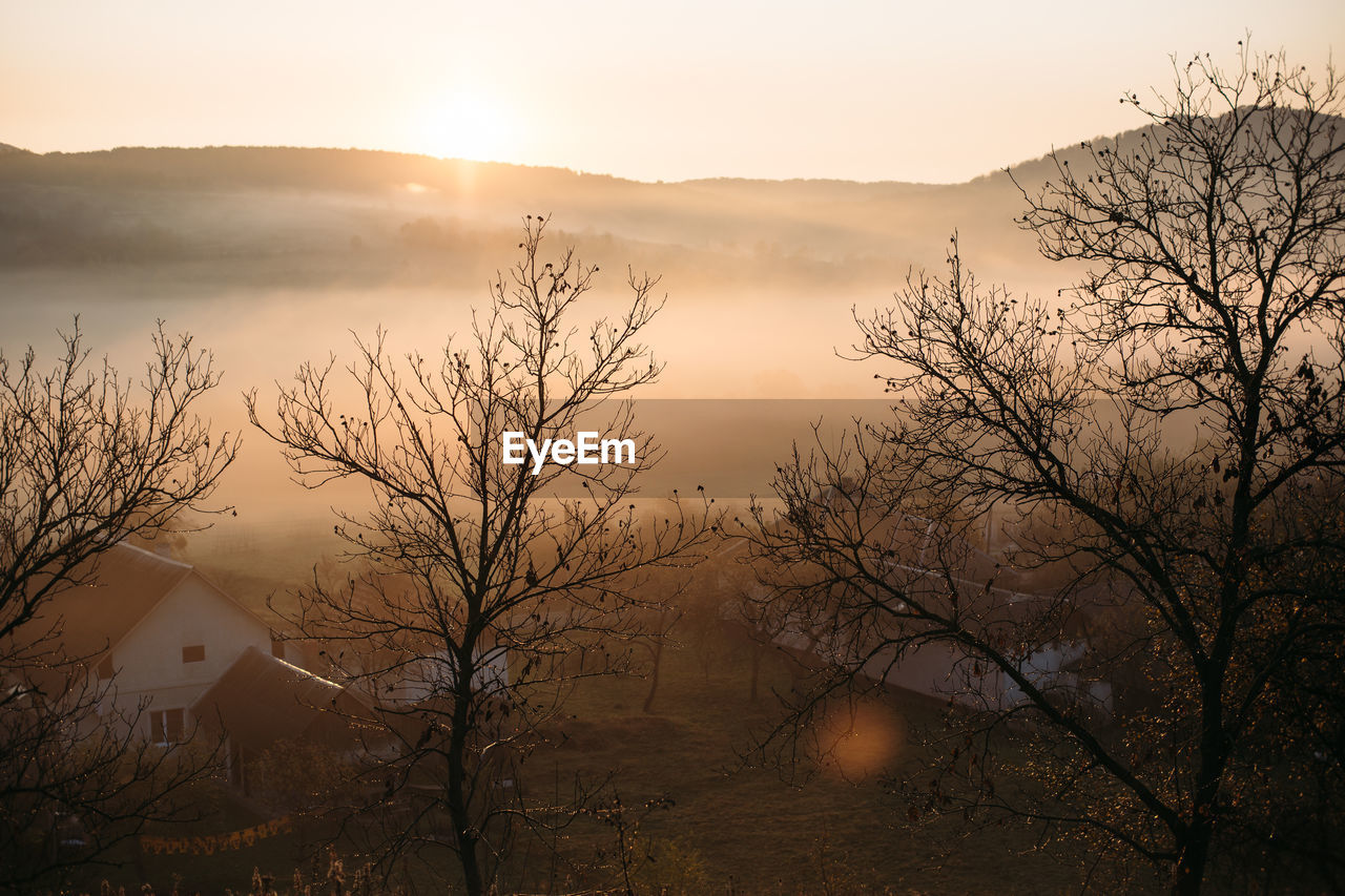 Foggy sunrise landscape in autumn mountains village