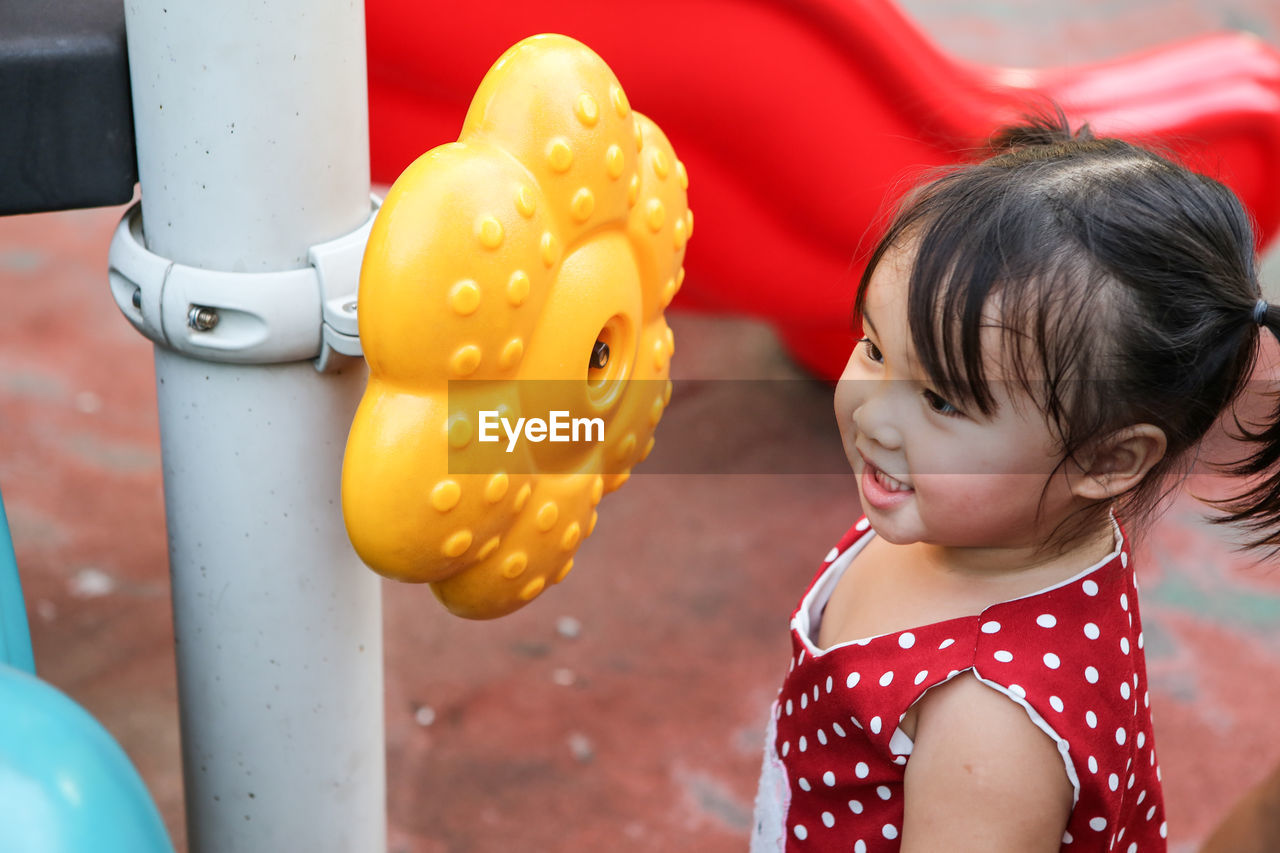 Close-up of cute girl looking yellow toy garlands on the playground