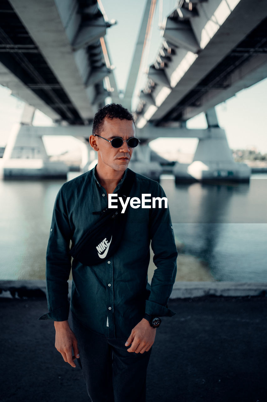 YOUNG MAN WEARING SUNGLASSES STANDING BY CAR