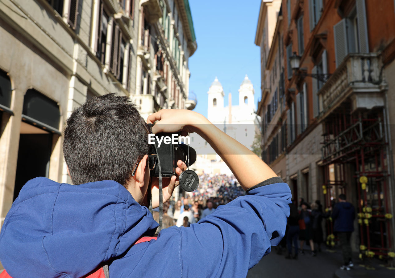 Rear view of teenage boy photographing church in city