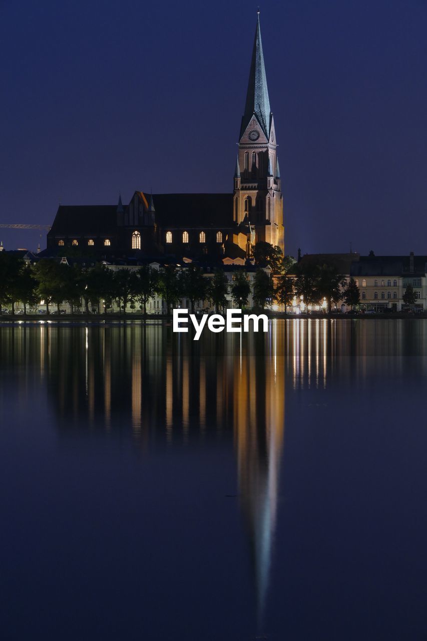 REFLECTION OF ILLUMINATED BUILDINGS IN LAKE AT NIGHT