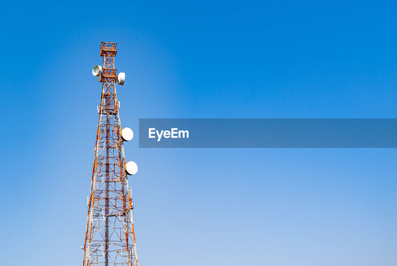 Low angle view of communications tower against blue sky