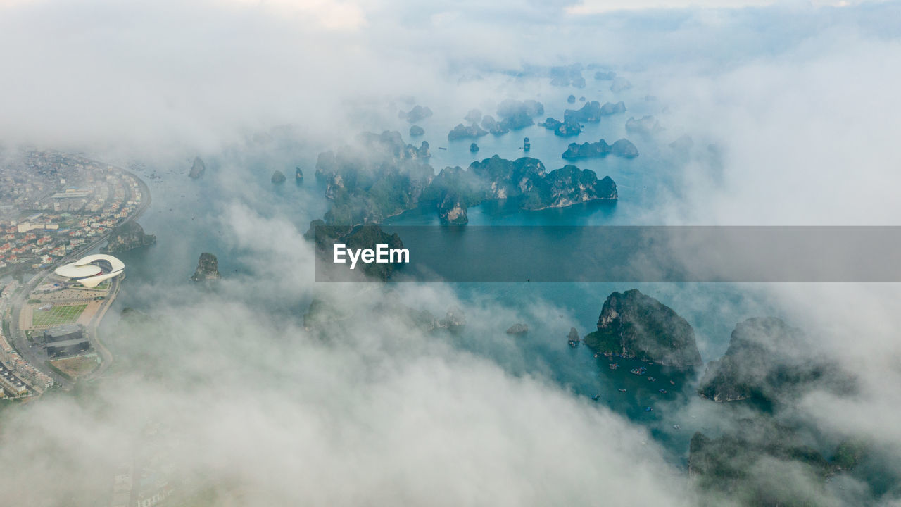 Aerial view of rock formations in sea seen through cloudy sky