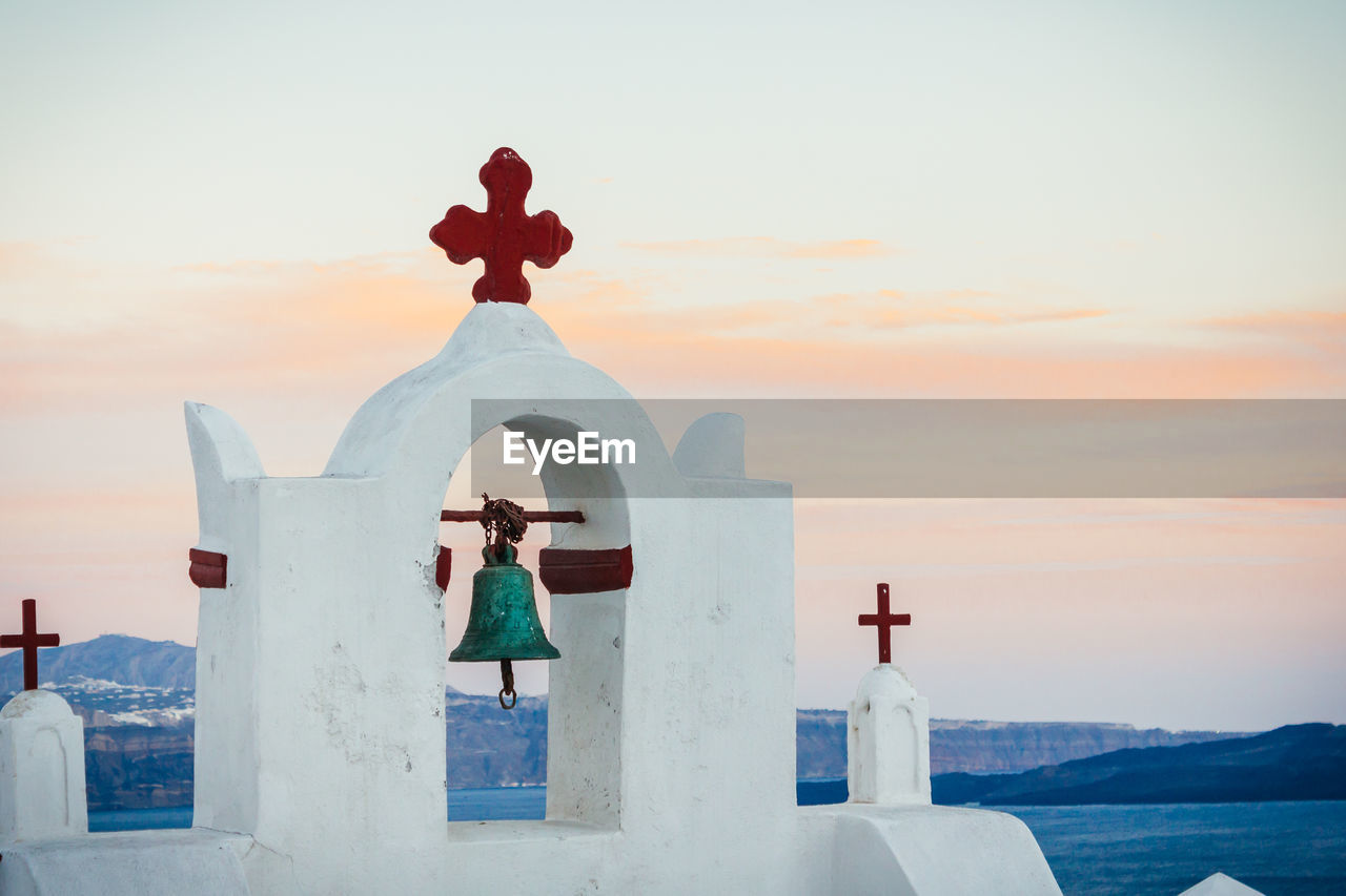 Chapel by sea against sky during sunset at santorini