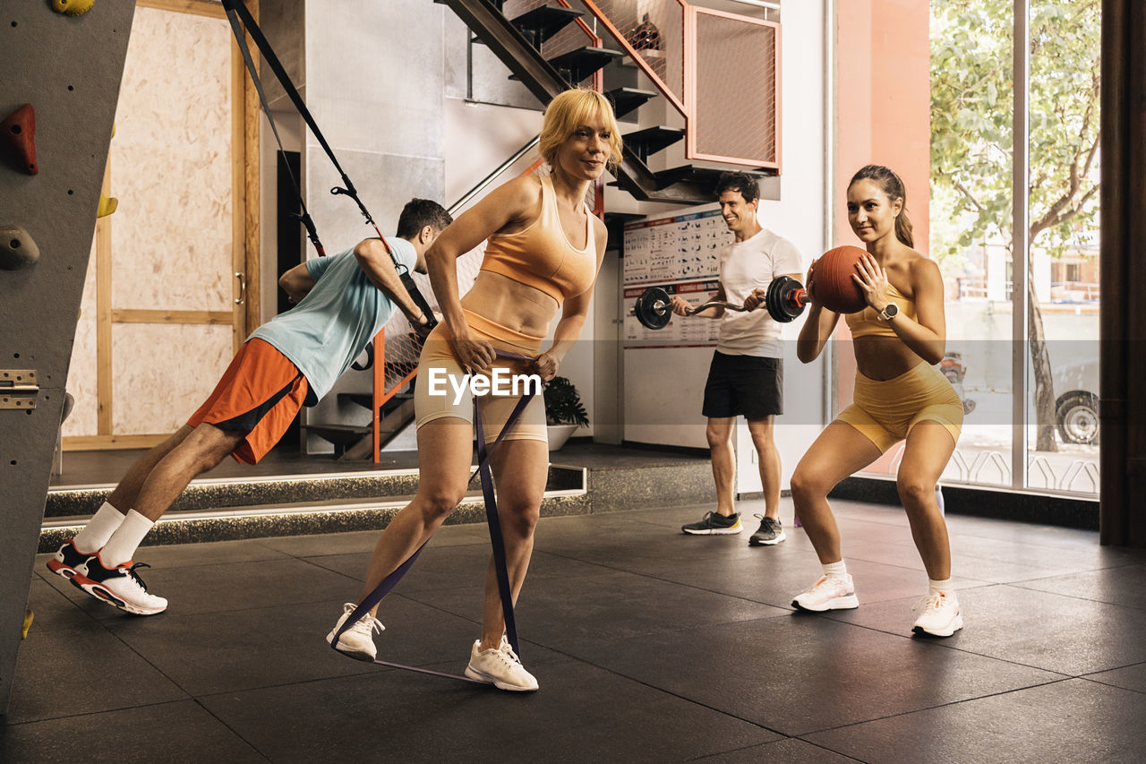 Group of young pro athletes performing different  exercises in the gym with a personal trainer.