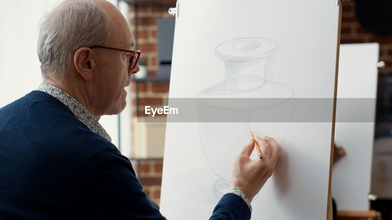 Senior man sketching on canvas