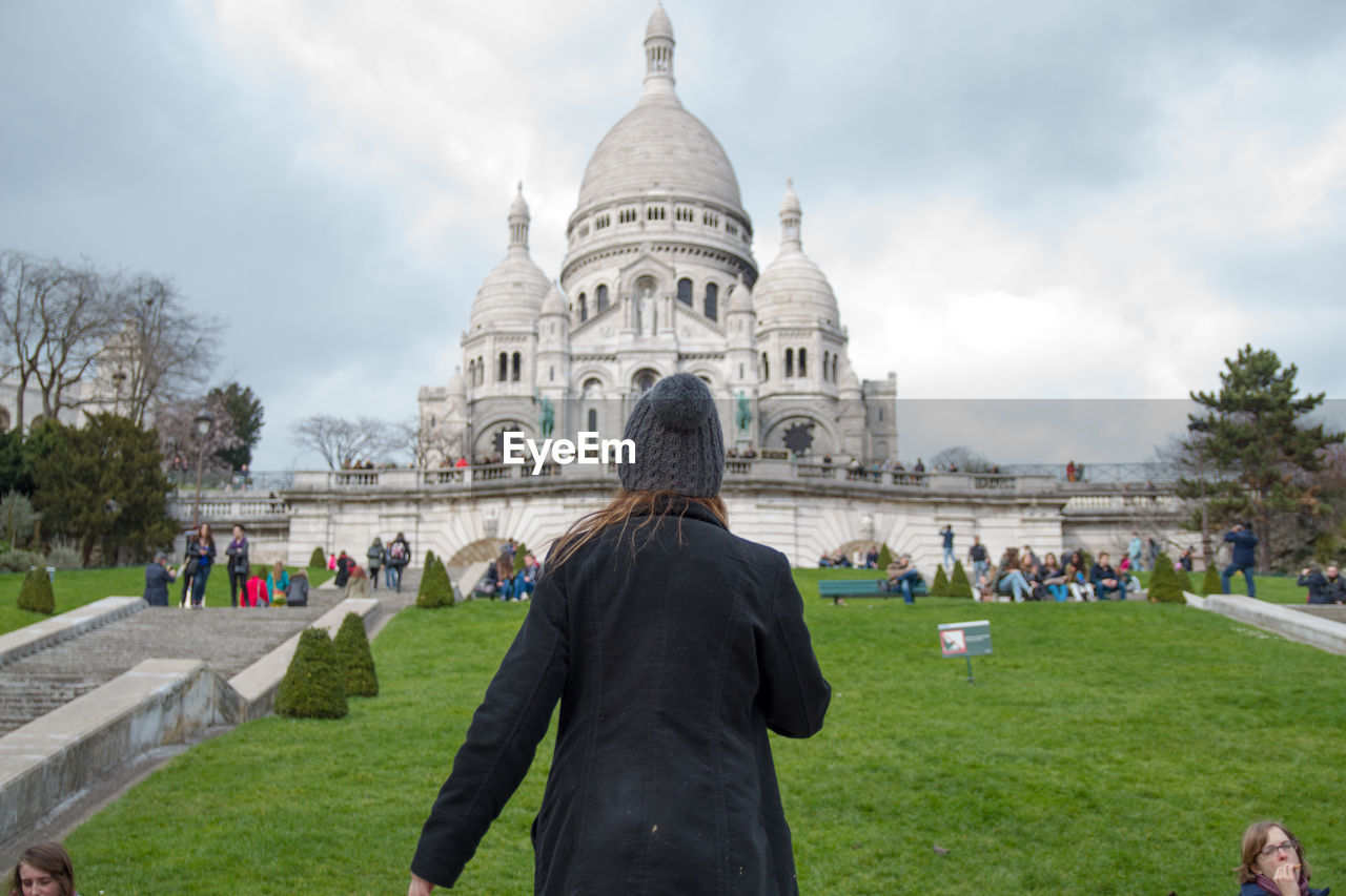 Rear view of woman standing on field against montmartre and sky