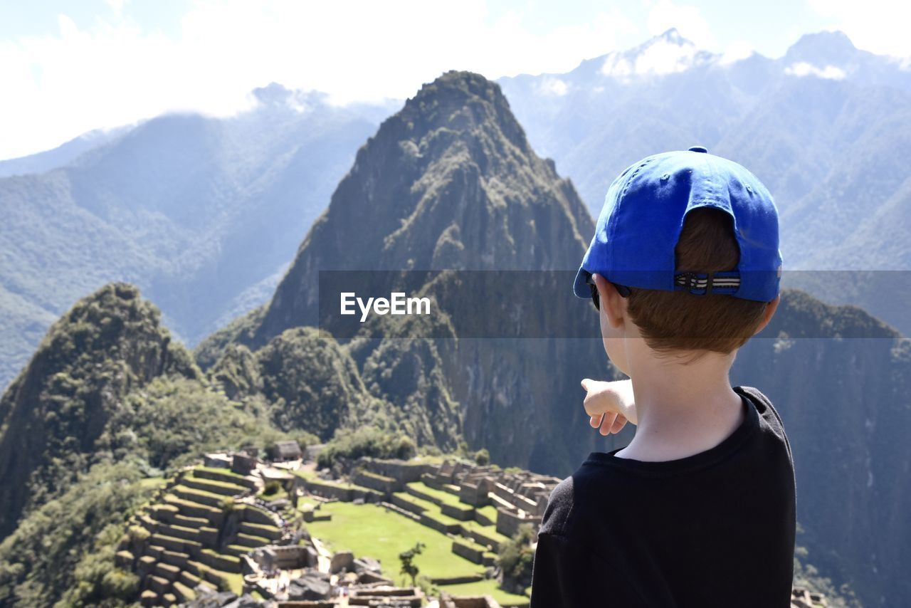 Rear view of boy looking at mountains against sky