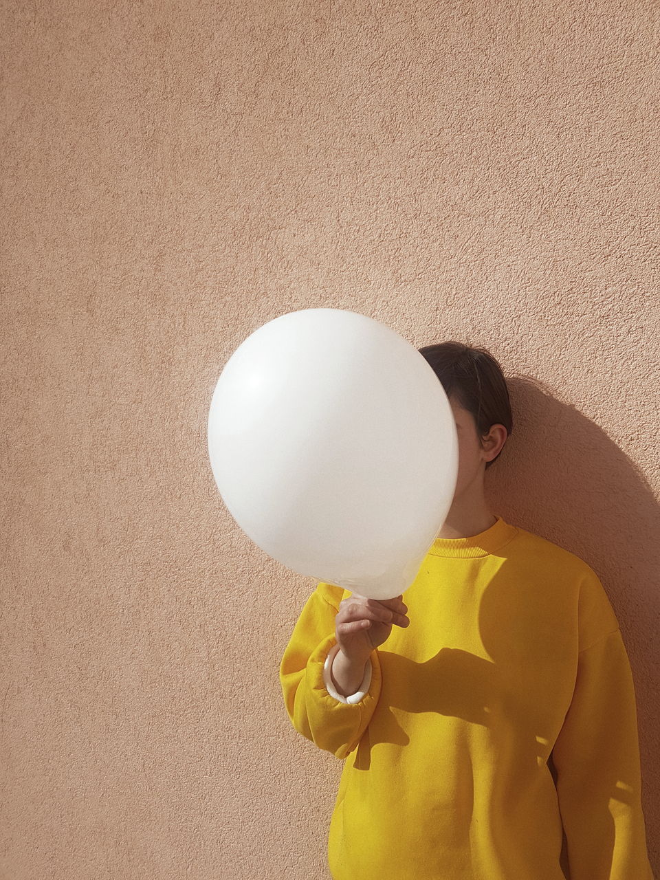 Man holding balloon against wall