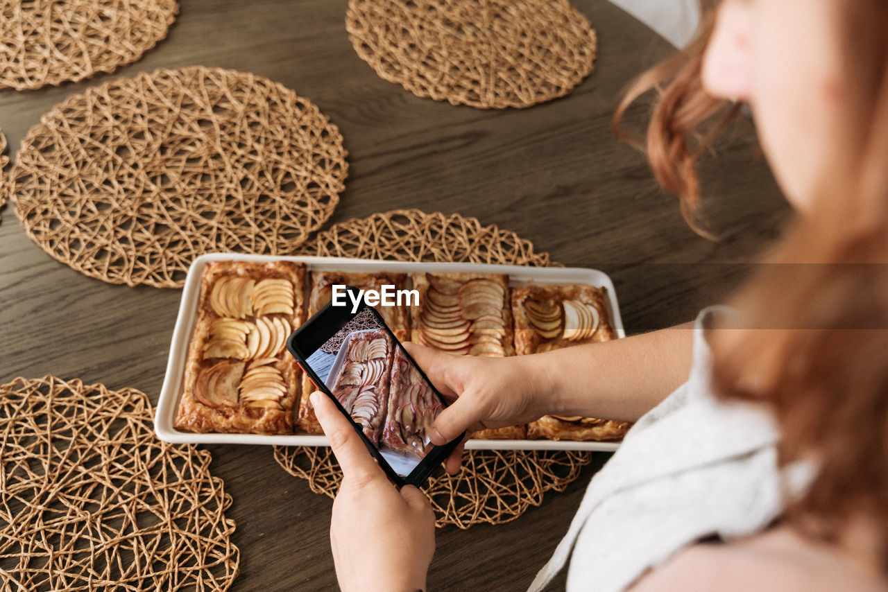 Female hands taking pictures of apple tart with mobile phone