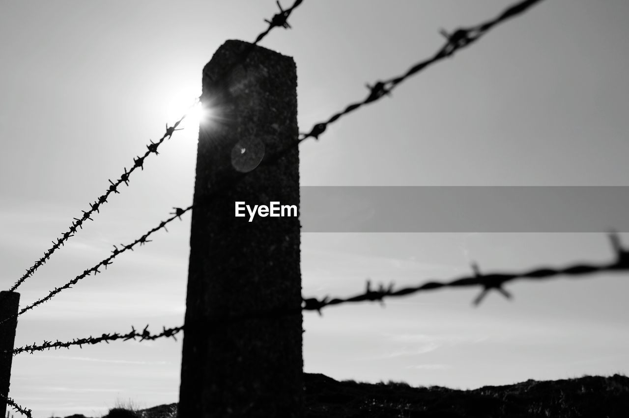 CLOSE-UP OF BARBED WIRE FENCE AGAINST SKY