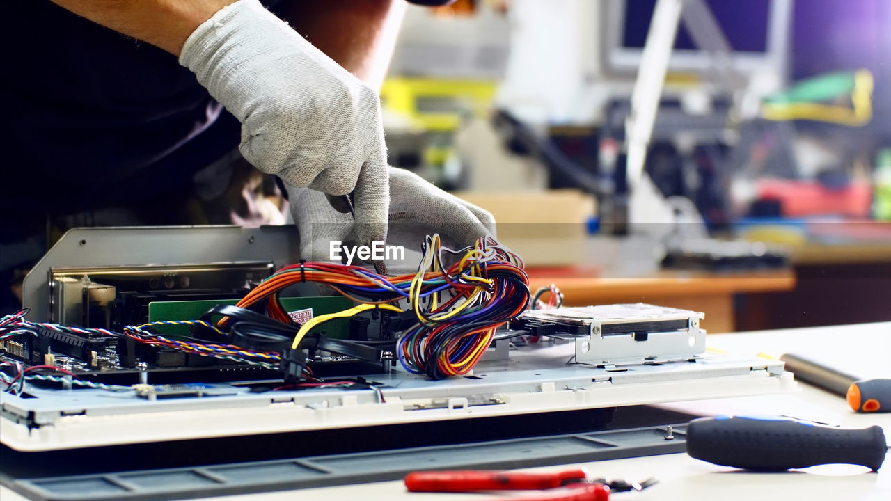 Midsection of man repairing computer equipment on table