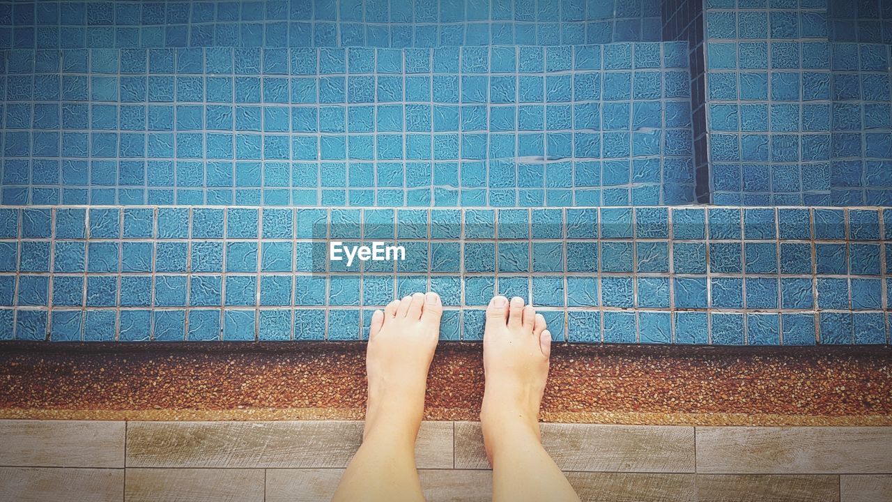 Low section of woman standing by swimming pool