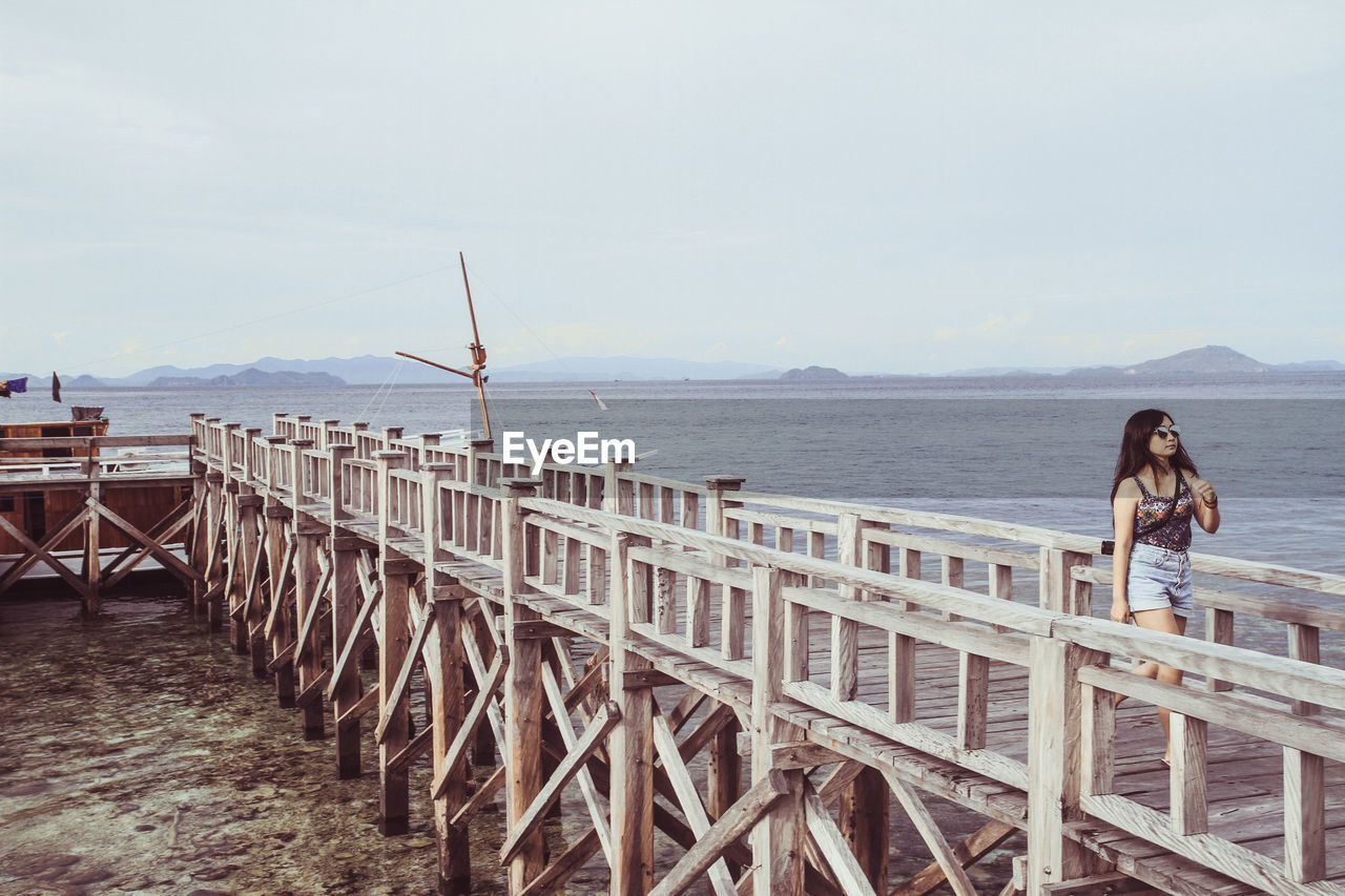 WOMAN BY RAILING AGAINST SEA