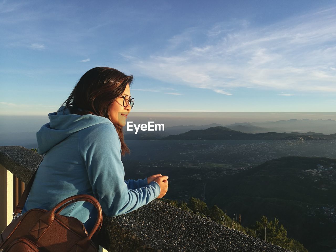 Side view of woman looking at landscape on mountain against sky during sunset