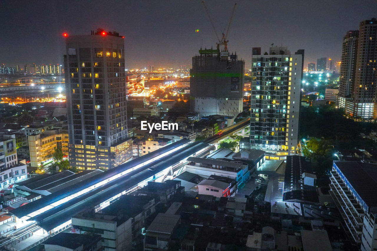 HIGH ANGLE VIEW OF ILLUMINATED STREET AMIDST BUILDINGS IN CITY AT NIGHT