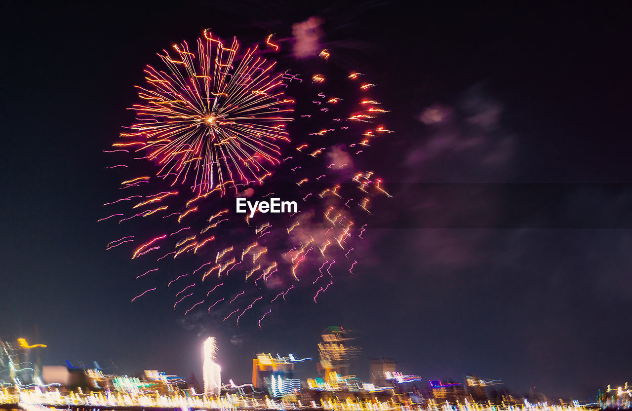 Firework in city against sky at night